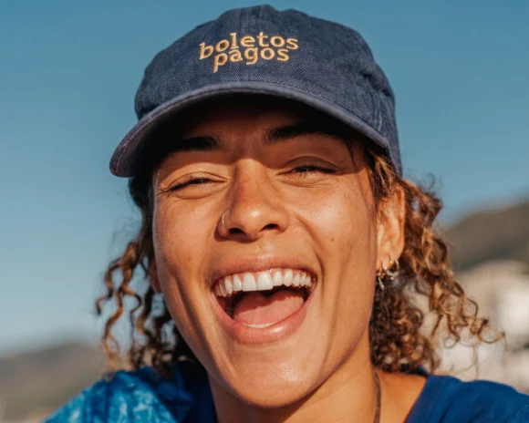 Pessoa sorridente segurando o celular com cartão de crédito e ícones de pagamento