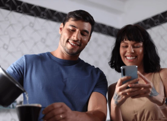Casal na cozinha com celular pagando contas pelo app