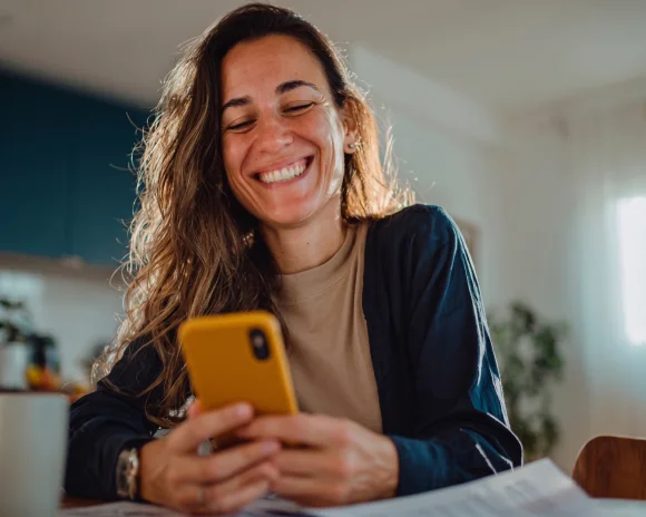 Mulher sorrindo enquanto paga contas pelo aplicativo RecargaPay no celular