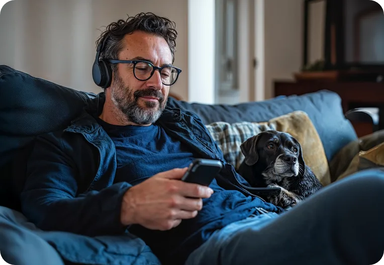 Homem usando o celular sentado ao lado de um cachorro.