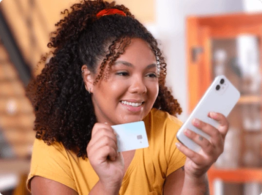 Mulher segurando celular e cartão de crédito para fazer Pix parcelado pelo RecargaPay