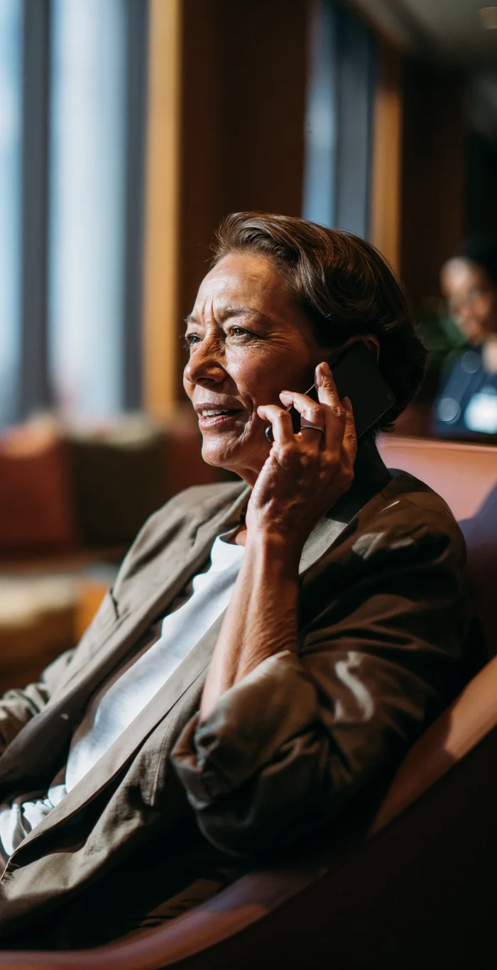 Mulher ao telefone sentada em uma sala de espera.